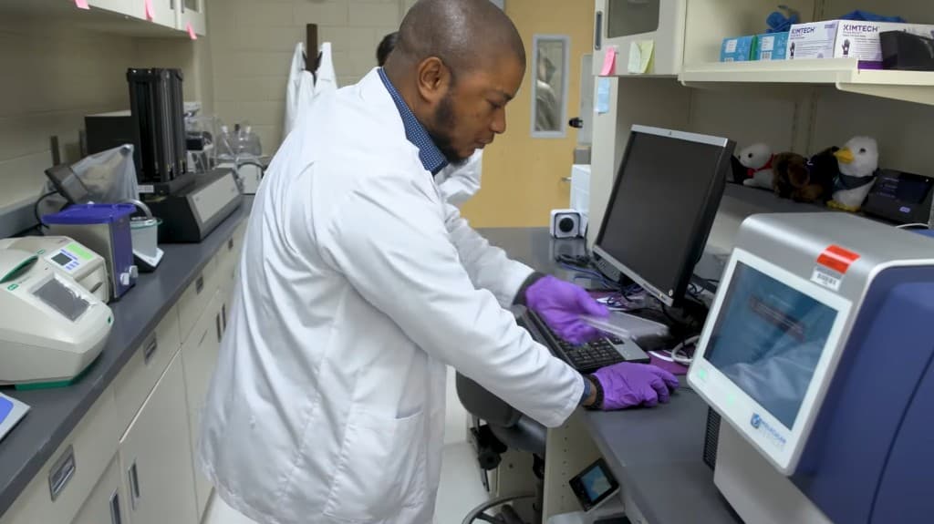 Researcher working with assay plates and instruments in the BioRacc Lab